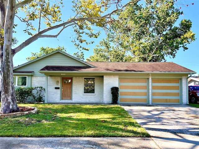 view of front of house featuring brick siding, a front yard, roof with shingles, a garage, and driveway