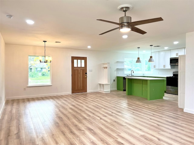 kitchen featuring open floor plan, a center island, recessed lighting, stainless steel appliances, and light wood finished floors