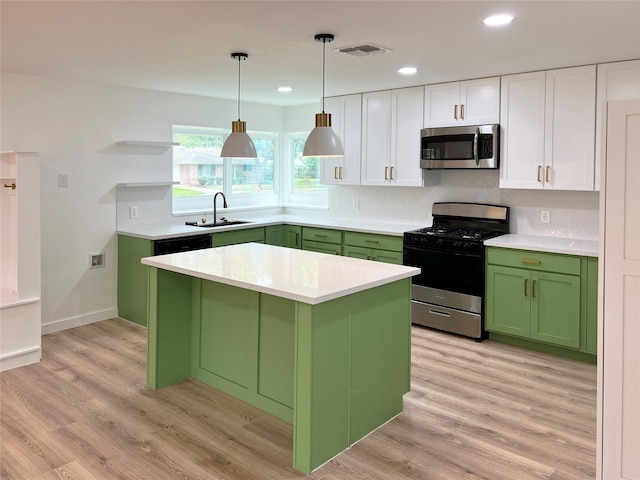 kitchen featuring range with gas stovetop, stainless steel microwave, a sink, and green cabinetry