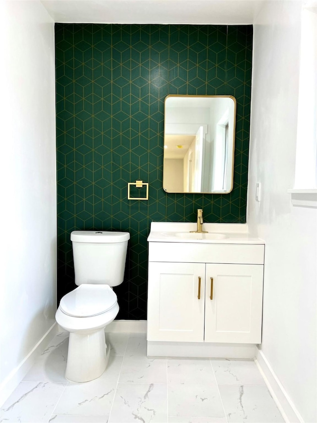 bathroom with baseboards, toilet, marble finish floor, and vanity