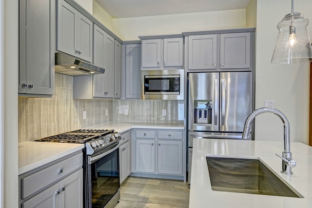 kitchen with pendant lighting, sink, tasteful backsplash, light hardwood / wood-style floors, and stainless steel appliances