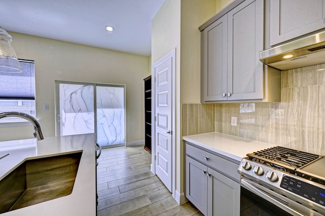 kitchen featuring gray cabinets, sink, extractor fan, and stainless steel range with gas stovetop