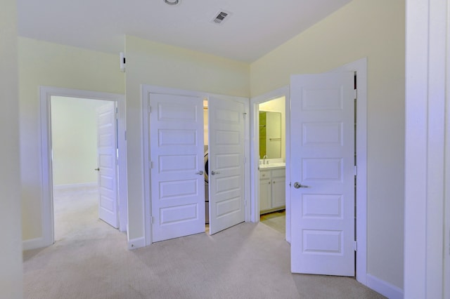 unfurnished bedroom featuring ensuite bathroom, sink, and light colored carpet