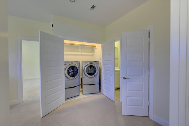 clothes washing area featuring light carpet and washer and clothes dryer