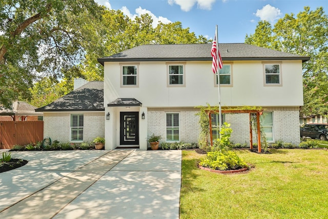 view of front of home featuring a front yard, fence, a shingled roof, a chimney, and brick siding