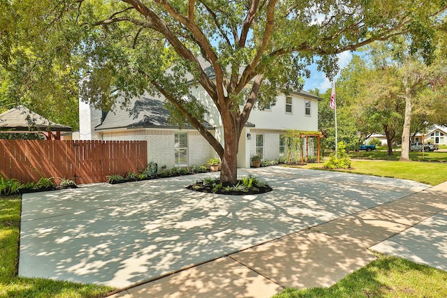 view of front of house with brick siding, a front lawn, and fence