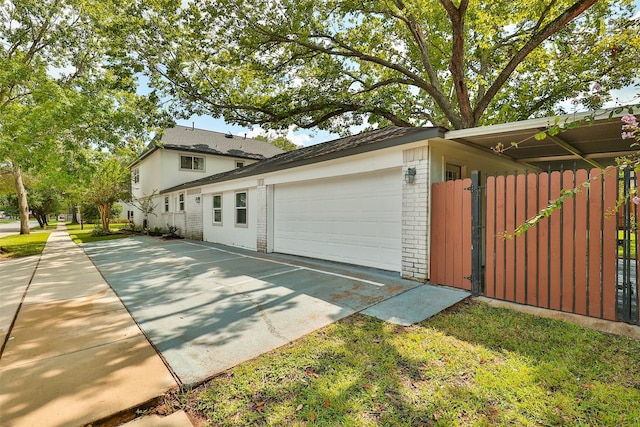 view of side of property with a garage, brick siding, and concrete driveway