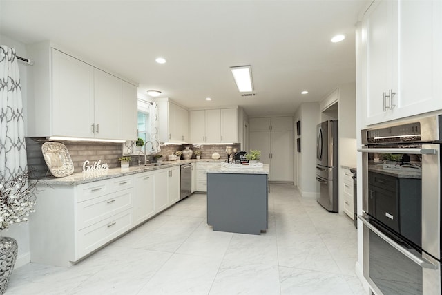 kitchen with white cabinets, tasteful backsplash, appliances with stainless steel finishes, and a center island