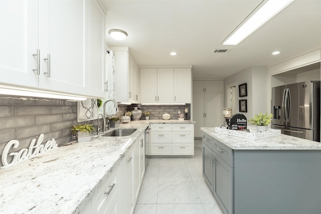 kitchen with marble finish floor, white cabinets, stainless steel appliances, and a sink