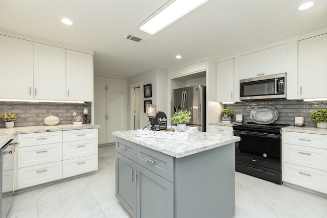 kitchen with gray cabinetry, appliances with stainless steel finishes, white cabinetry, and decorative backsplash