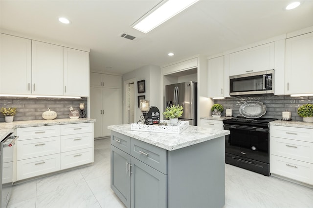 kitchen with visible vents, marble finish floor, a kitchen island, white cabinetry, and appliances with stainless steel finishes