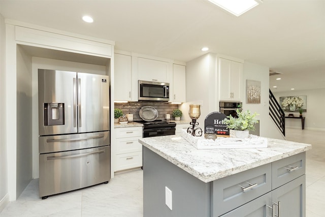 kitchen with light stone countertops, tasteful backsplash, appliances with stainless steel finishes, and a kitchen island