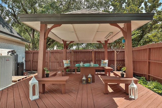 wooden deck featuring a gazebo, central air condition unit, and a fenced backyard