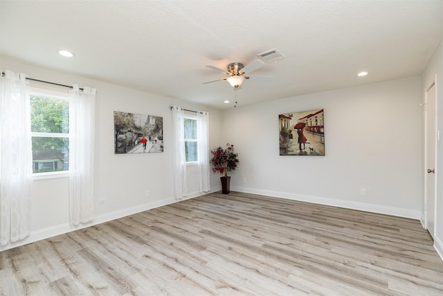 unfurnished room with a ceiling fan, wood finished floors, a healthy amount of sunlight, and visible vents