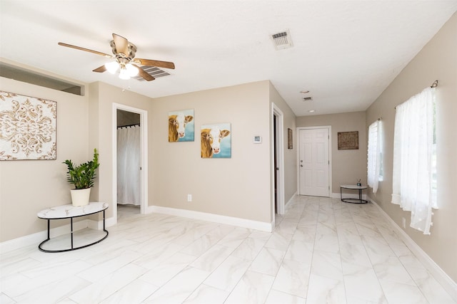 interior space with visible vents, marble finish floor, baseboards, and a ceiling fan