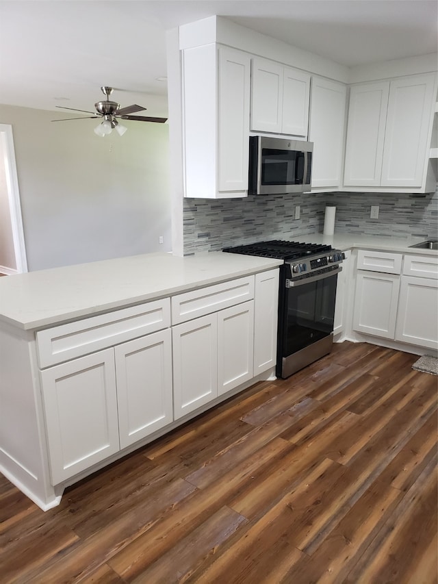 kitchen with stainless steel appliances, white cabinetry, kitchen peninsula, tasteful backsplash, and dark hardwood / wood-style flooring