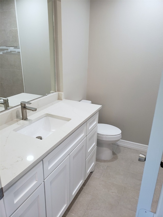 bathroom with toilet, vanity, and tile patterned floors