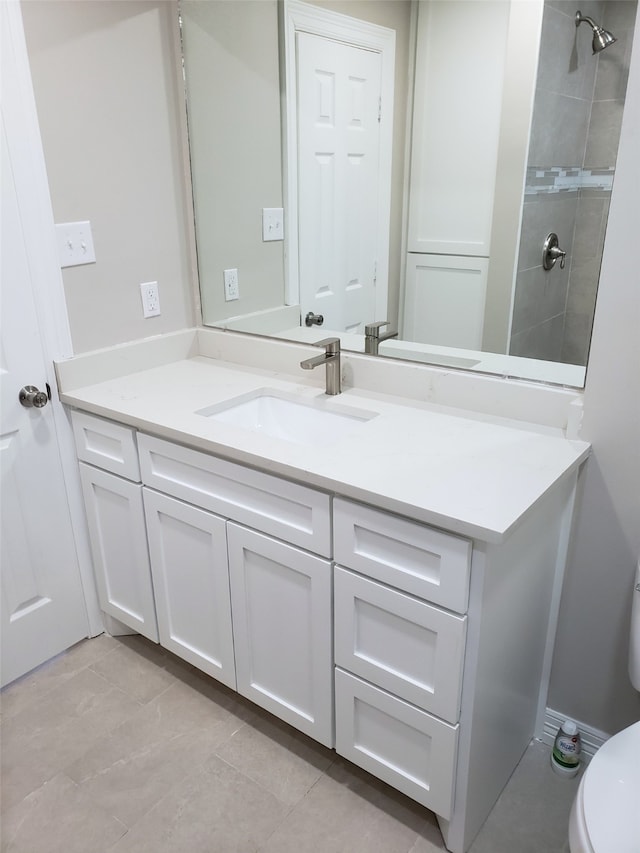 bathroom with toilet, vanity, tile patterned floors, and tiled shower