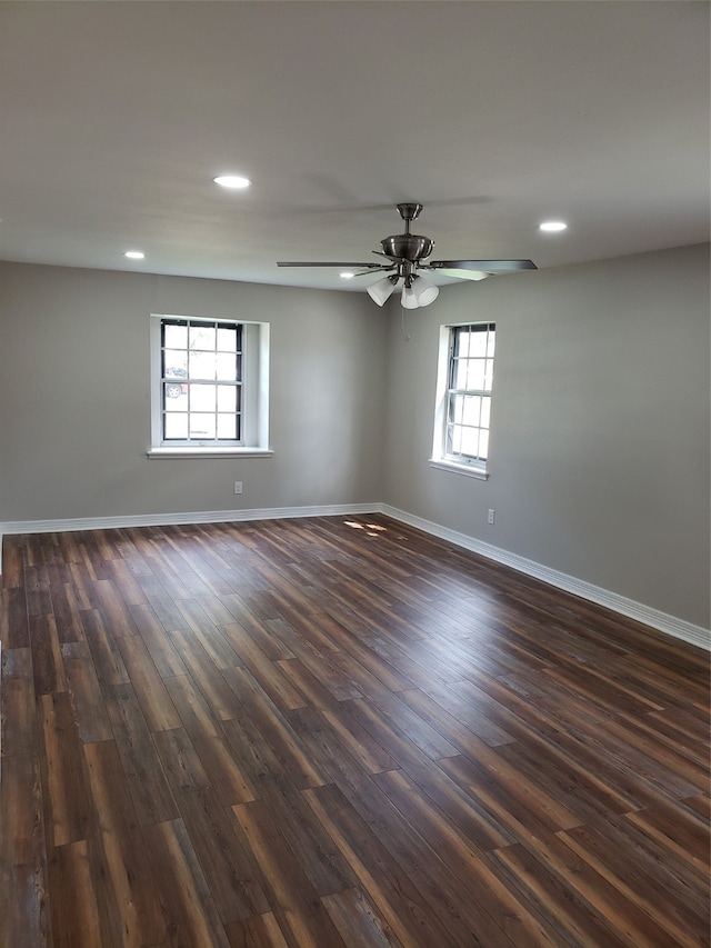 unfurnished room featuring ceiling fan, a wealth of natural light, and dark hardwood / wood-style floors