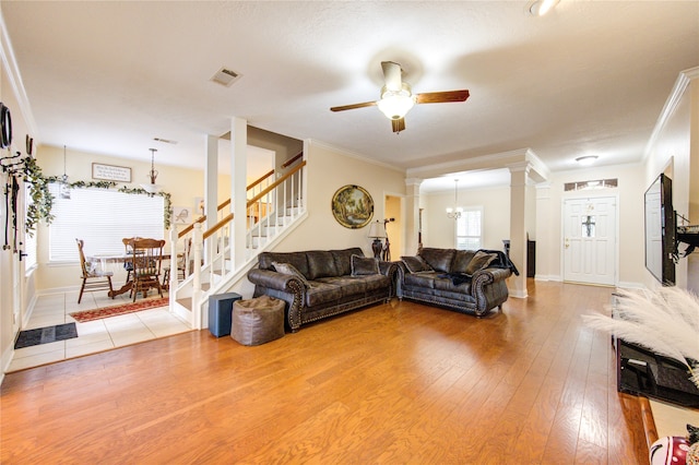 living room featuring wood-type flooring, ceiling fan, decorative columns, and crown molding