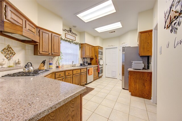 kitchen featuring sink, stainless steel appliances, backsplash, and light tile patterned floors