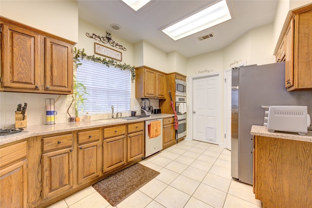 kitchen with backsplash, light tile patterned flooring, sink, and stainless steel appliances