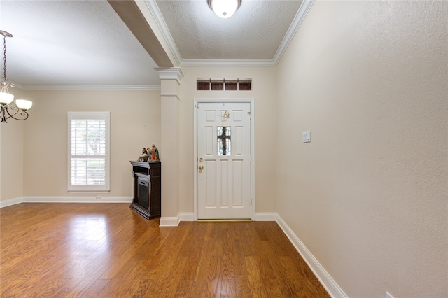 foyer with an inviting chandelier, hardwood / wood-style flooring, and ornamental molding