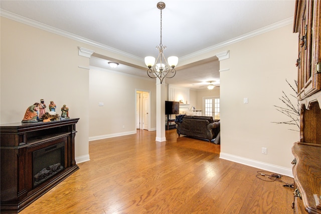 interior space featuring an inviting chandelier, light hardwood / wood-style flooring, crown molding, and ornate columns