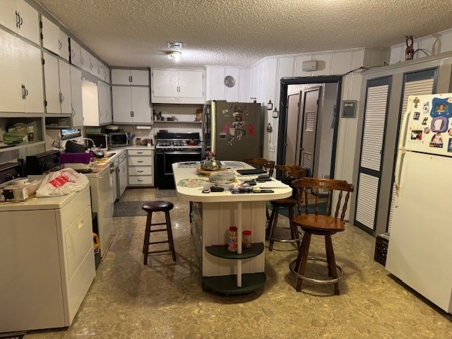 kitchen featuring stainless steel fridge, white cabinetry, white fridge, a textured ceiling, and black range with gas cooktop