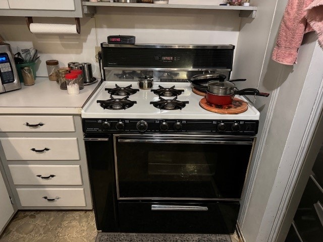 kitchen with white range with gas stovetop and white cabinetry