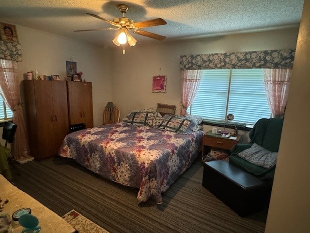 bedroom featuring ceiling fan, a textured ceiling, and dark carpet