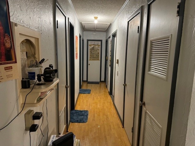 hall featuring light wood-type flooring and a textured ceiling