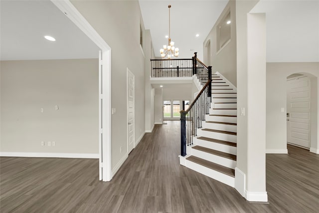 entrance foyer with dark wood-type flooring, an inviting chandelier, and a towering ceiling