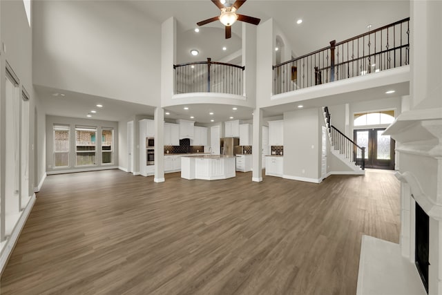 unfurnished living room with ceiling fan, dark hardwood / wood-style floors, sink, and a towering ceiling