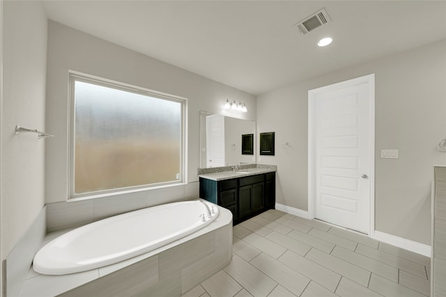 bathroom featuring tiled bath and vanity