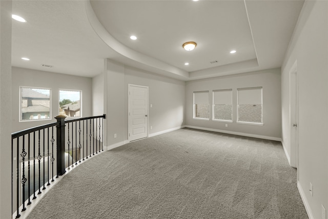 carpeted spare room with a tray ceiling