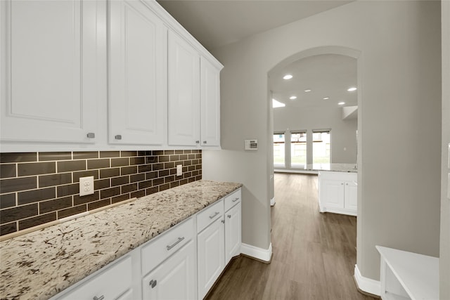 kitchen featuring white cabinets, light stone counters, dark hardwood / wood-style floors, and tasteful backsplash