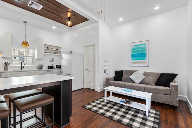 kitchen with hanging light fixtures, white appliances, sink, and white cabinets