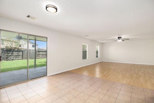 tiled empty room with a textured ceiling, ceiling fan, and a healthy amount of sunlight