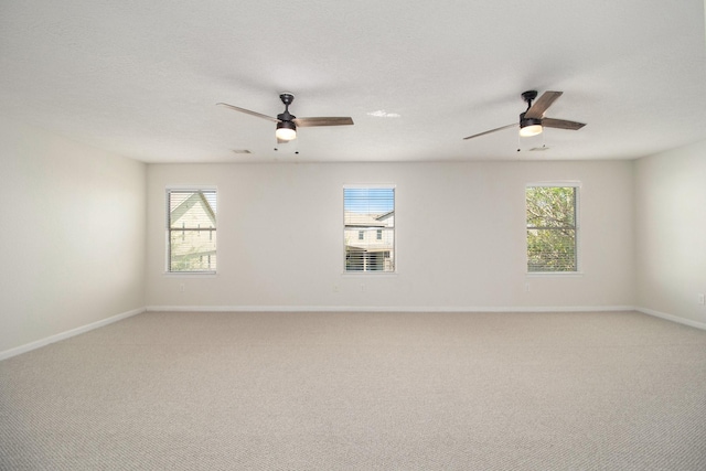 carpeted spare room featuring ceiling fan and plenty of natural light