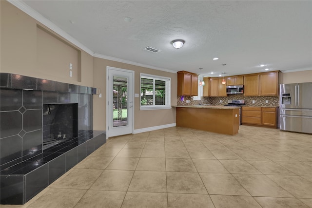 kitchen with a fireplace, light tile patterned floors, stainless steel appliances, ornamental molding, and kitchen peninsula