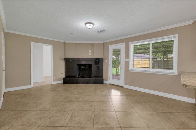 unfurnished living room with a textured ceiling, crown molding, light tile patterned floors, and a tile fireplace