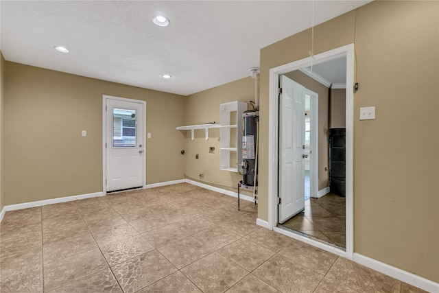 foyer featuring light tile patterned floors, ornamental molding, a textured ceiling, and water heater