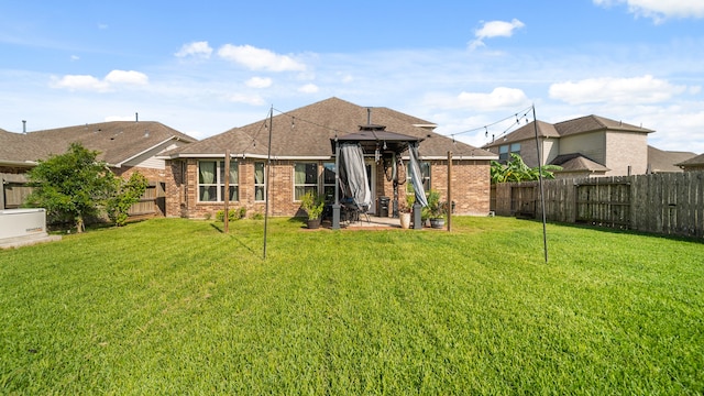 back of property with a yard and a gazebo