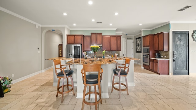 kitchen with appliances with stainless steel finishes, a large island with sink, decorative backsplash, and a breakfast bar