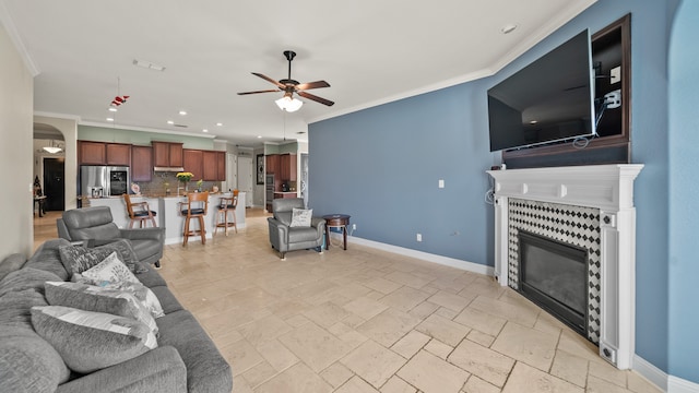 living room featuring ceiling fan, a fireplace, and crown molding