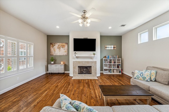 living room featuring hardwood / wood-style flooring, ceiling fan, and a fireplace