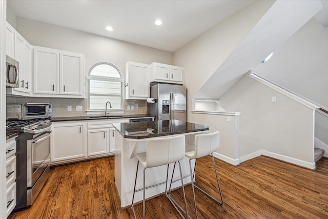 kitchen featuring a kitchen island, appliances with stainless steel finishes, white cabinetry, sink, and decorative backsplash