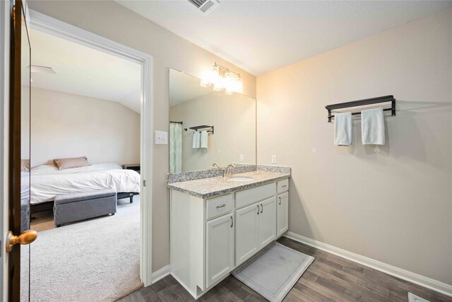 bathroom with vanity, wood-type flooring, and vaulted ceiling