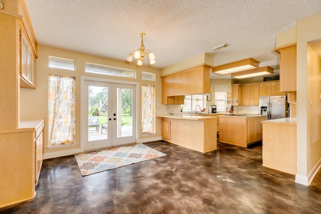 kitchen with a textured ceiling, light brown cabinetry, sink, and stainless steel fridge